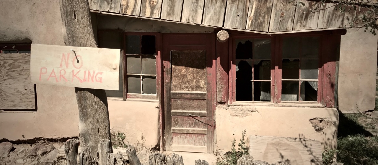 Broken-down house with shattered windows and No Parking sign