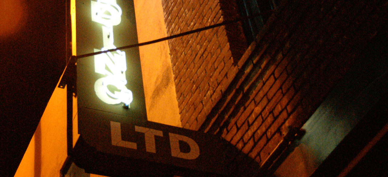 Neon sign on brick building, at night