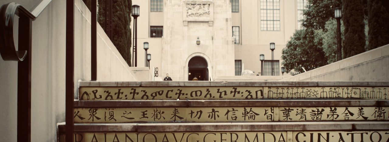 Steps, with writing on them in multiple languages, leading to a marble door