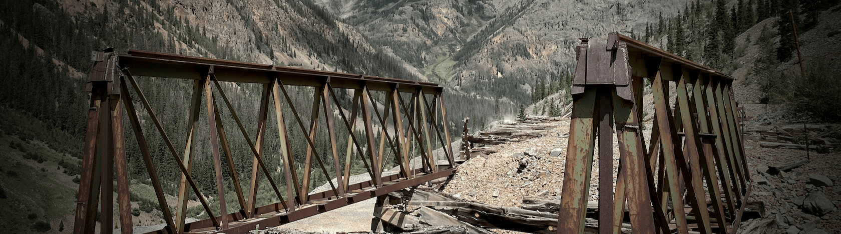 A rusted trestle bridge in a high-altitude Rocky Mountain view