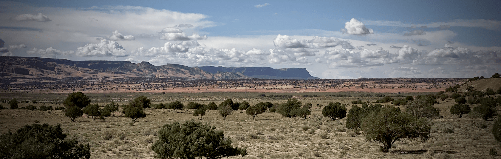 A green butte under a wide blue sky