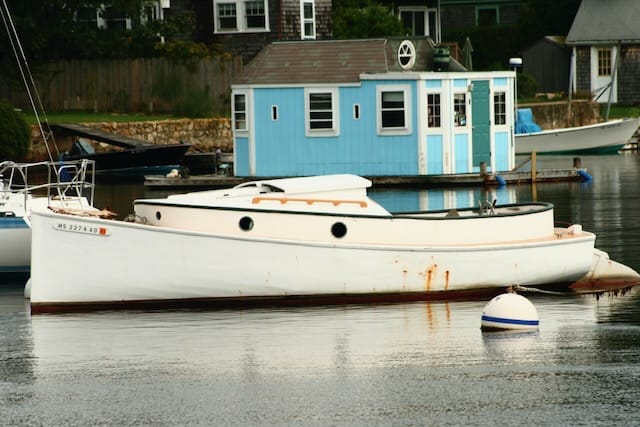 A small cabin sailboat on the water, sail down.